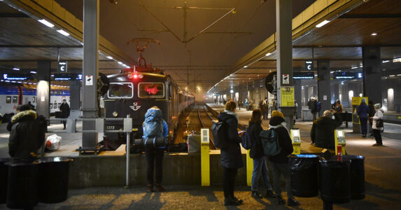 Trängsel på en järnvägsperrong en regnig kväll.