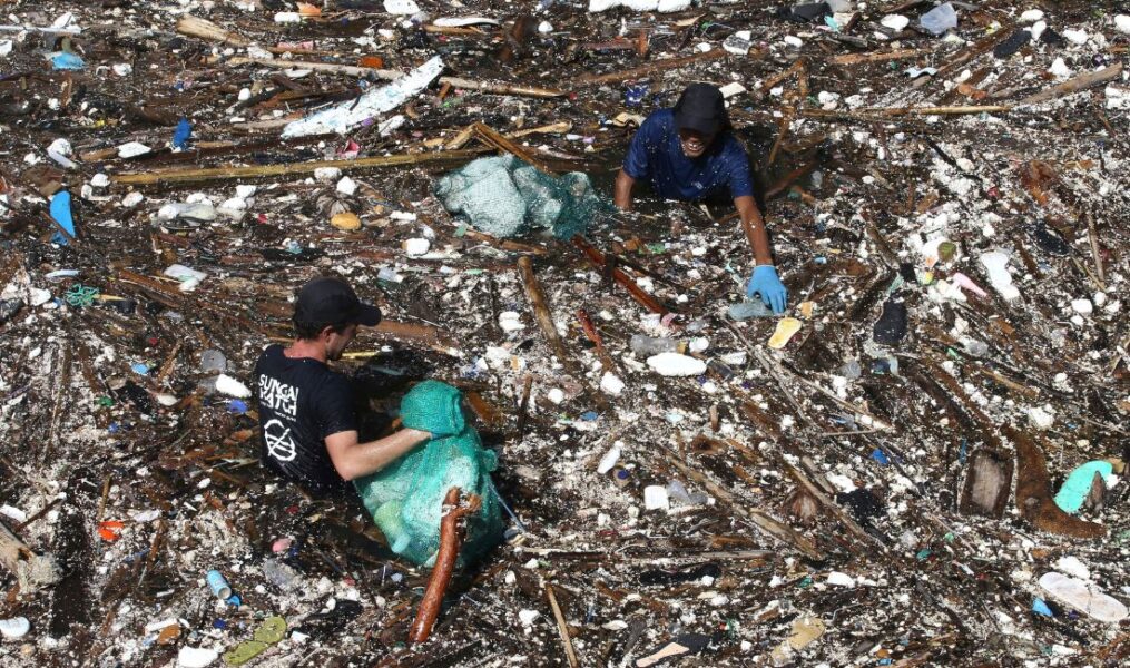 Man samlar plast i en nedskräpad flod i Indonesien.