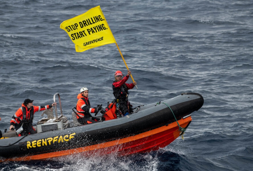 Aktivister på en liten båt med en banner med budskapet: Stop drilling start paying.