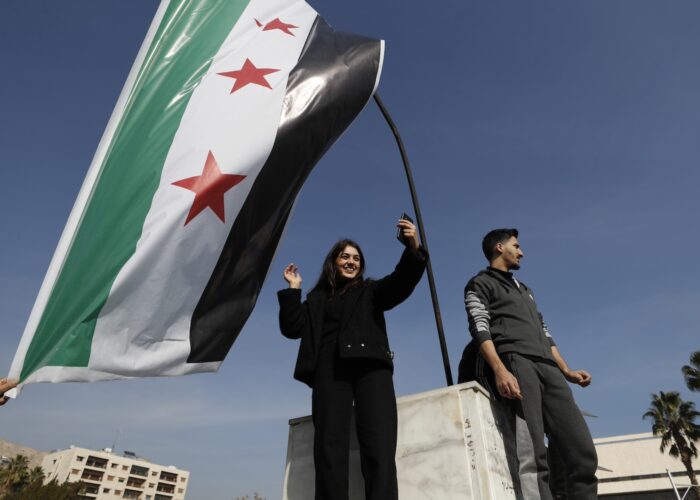 En kvinna viftar med oppositionens/rebellernas nya Syrienflagga.