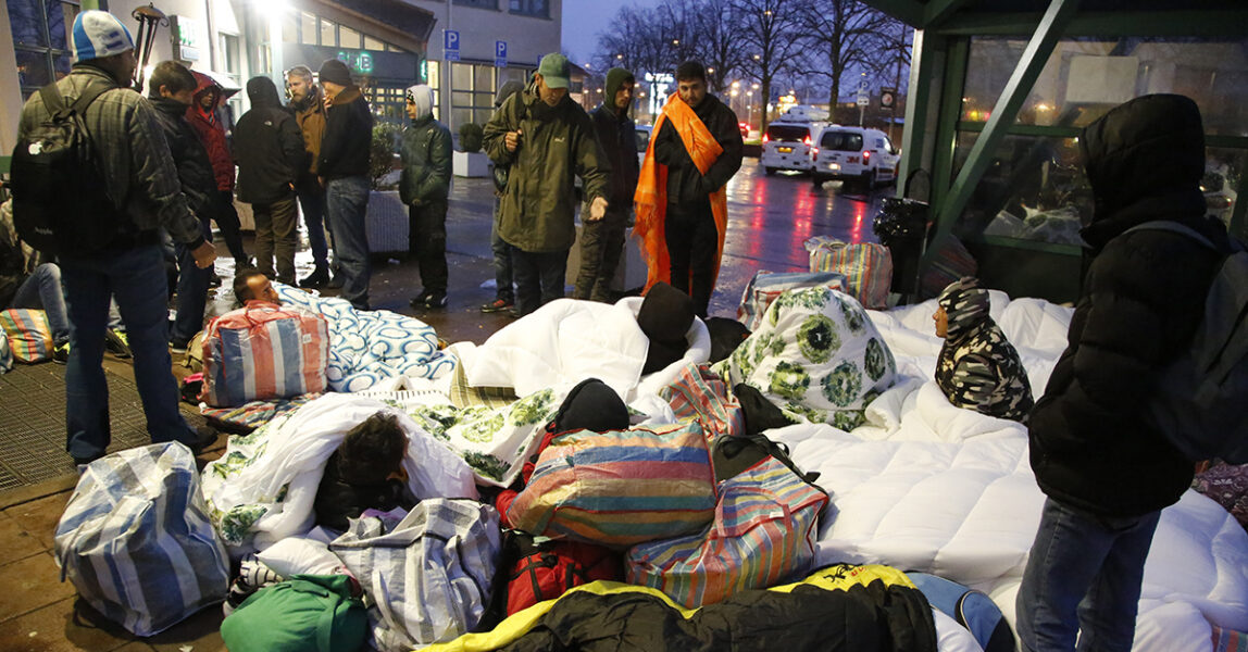 En man sitter i en bädd för flera personer på en trottoar.