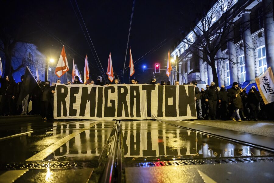 Demonstranter håller en banderoll med texten remigration.