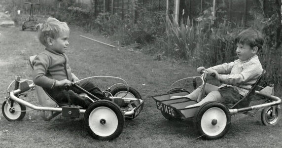 Två små killar i gokarts som de använder som rullstolar.