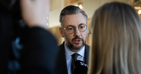 Den avgående Centerpartiledaren tittar fram mellan två reportrar.