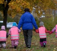 En barngrupp promenerar med sin förskollärare/barnskötare.