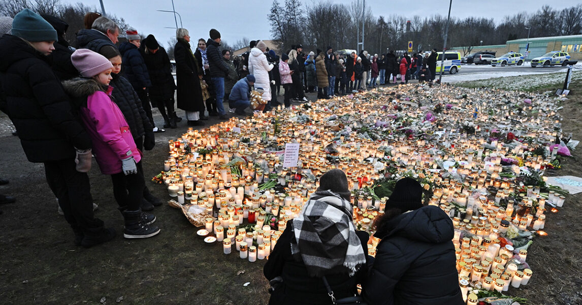 Sörjande människor framför blommor och ljus.