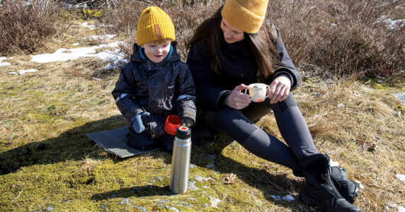 Barn, mamma och termos i gräset.