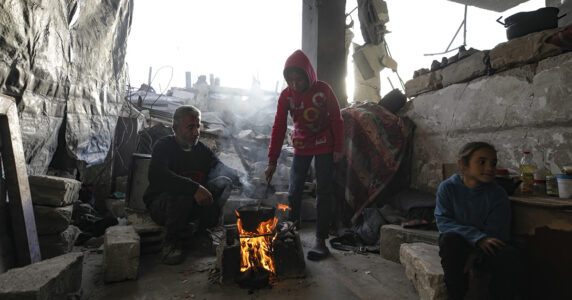 En familj lagar middag bland ruiner.