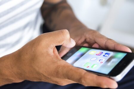 Händer håller i en mobil med sociala medier-appar.