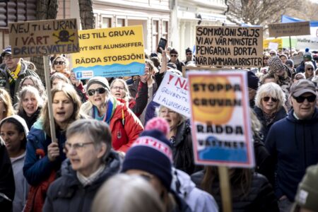 Demonstranter håller i plakat med budskap om att stoppa gruvplaner.