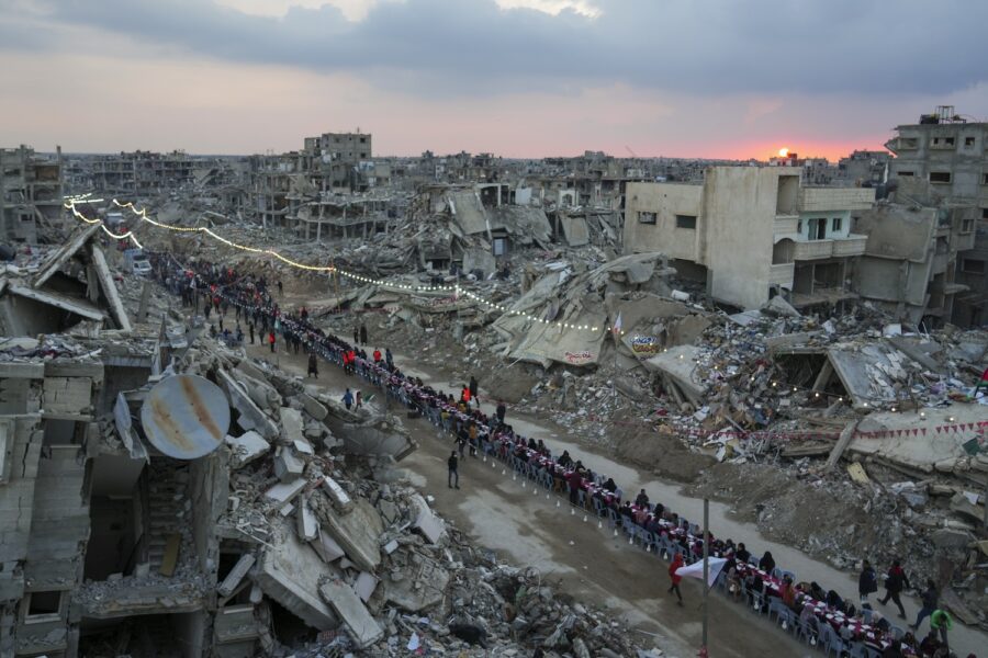 Gazabor sitter runt ett långbord för att fira Ramadan, mitt bland ruinerna i Gaza.