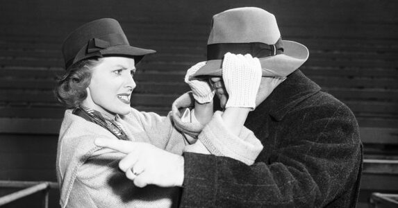 En arg kvinna trycker ner hatten över ögonen på en man.