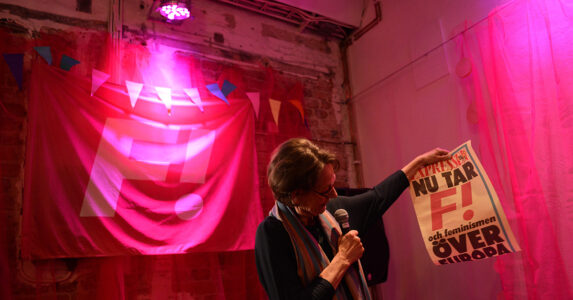 Kvinna på en rosa scen med en löpsedel.