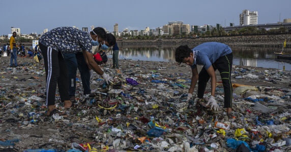 Pojkar plockar skräp vid en flodstrand.