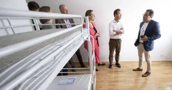 Ministrar visas runt på förläggning med våningssängar.