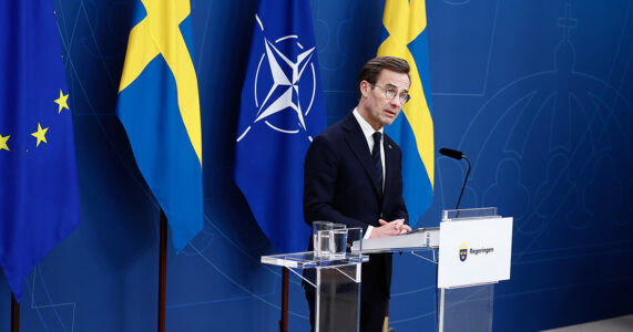 Statsminister bland blågula flaggor.