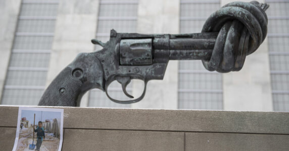 Skulptur av en pistol med knut och en bild av ett barn.