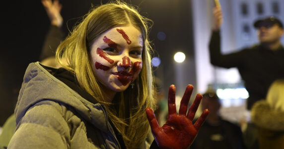 Ung demonstrant med ett målat rött handavtryck i ansiktet.