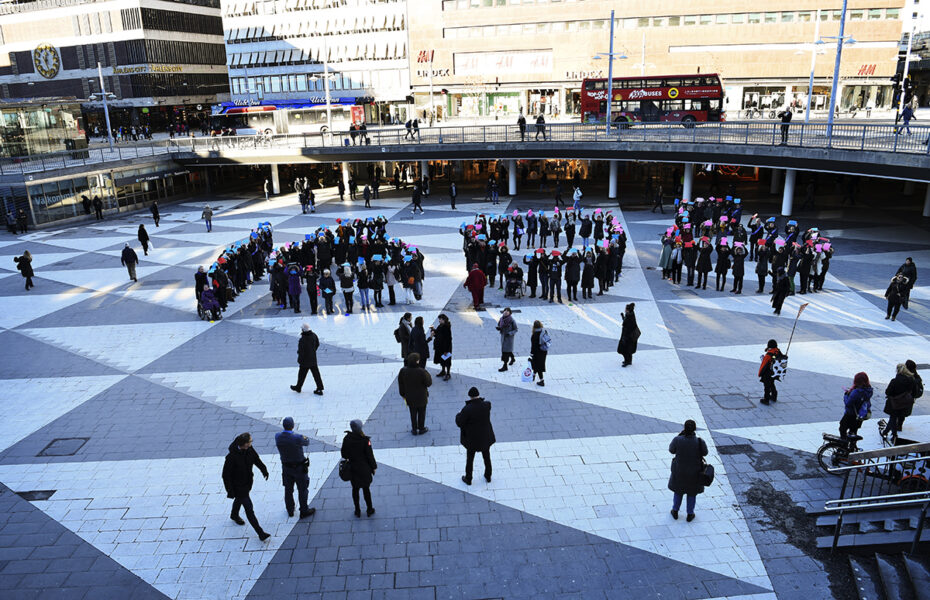 människor på Sergels torg formar klockslag