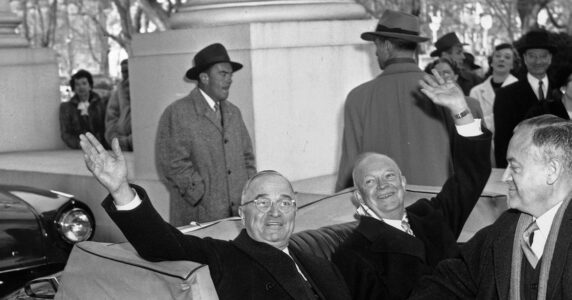 Tre män i en bil varav två vinkar.