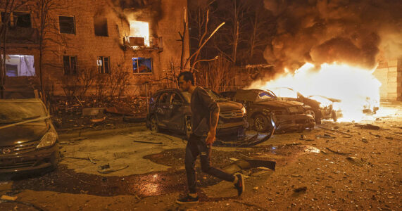 Någon springer över en bombad gata.