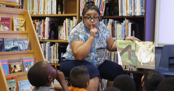 En kvinna läser sagor för en grupp barn på ett bibliotek.