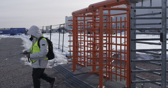 En man i arbetskläder går ut genom en grind.