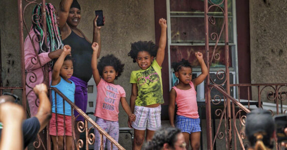 Barn med knutna nävar i luften. En demonstration går förbi.