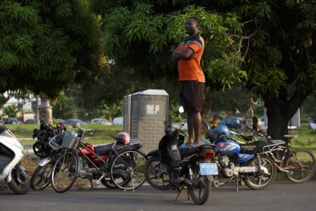 En man står på en moped för att kunna se bättre.