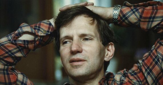 Porträtt av en man med händerna knäppta på huvudet.