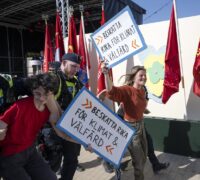 Två aktivister med glada miner förs bort av polisen.