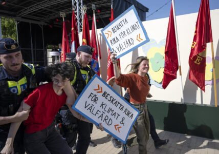 Två aktivister med glada miner förs bort av polisen.