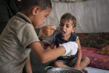 En liten pojke matas av en äldre pojke.