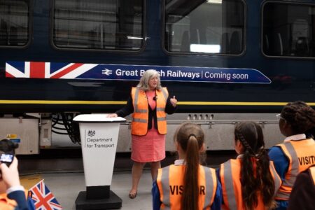 Transportminister Heidi Alexander framför ett tåg med logon: Great British railways – coming soon.