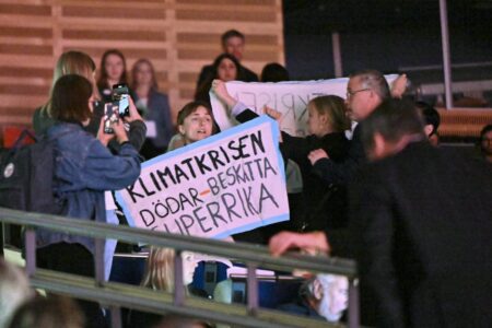 Klimataktivister med banderoller i publiken på S-kongressen.