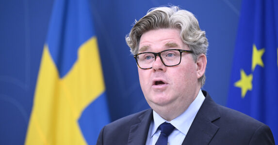 Justitieminister Gunnar Strömmer framför en svensk flagga.