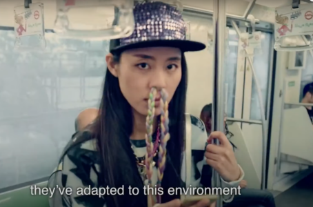 Moderiktig tjej står på tunnelbanan med flätat näshår i ljusa pastellfärger som kommer utifrån hennes näsborrar.