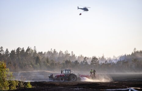 Helokopter och traktor släcker skog och mark.