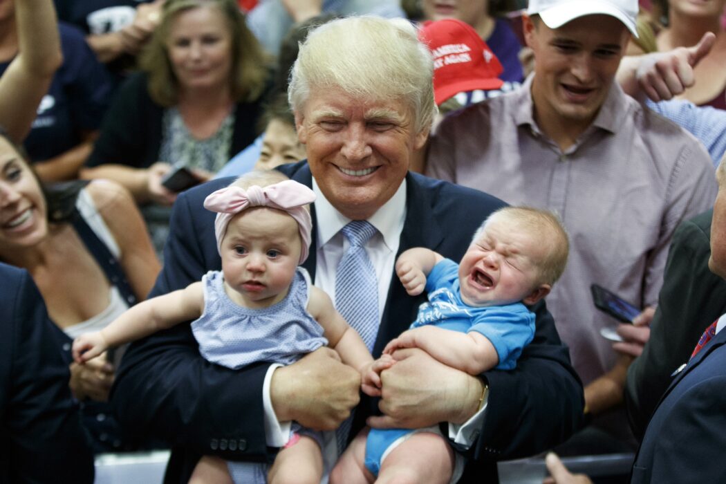 Donald Trump håller i två bebisar, en av dem gråter.