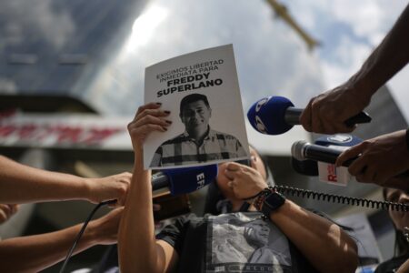 En person håller ett papper med en bild på en gripen oppositionsledare: Freddy Superlano.