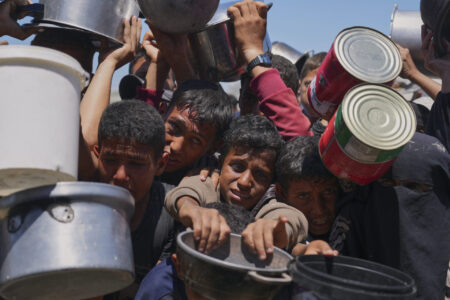 Svältande barn sträcker fram matskålar.