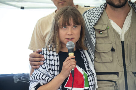 Greta Thunberg med mikrofon och Ship to Gaza-tröja.