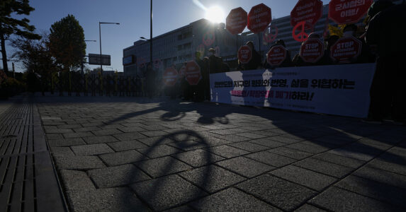 En skugga av ett fredsmärke framför en fredsmanifestation.