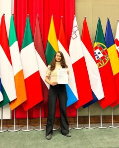 Rebecka Le Moine framför flaggor med dokument i handen