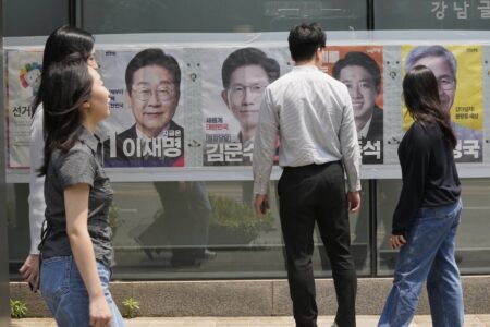 Människor går förbi och tittar på valaffischer på en vägg.