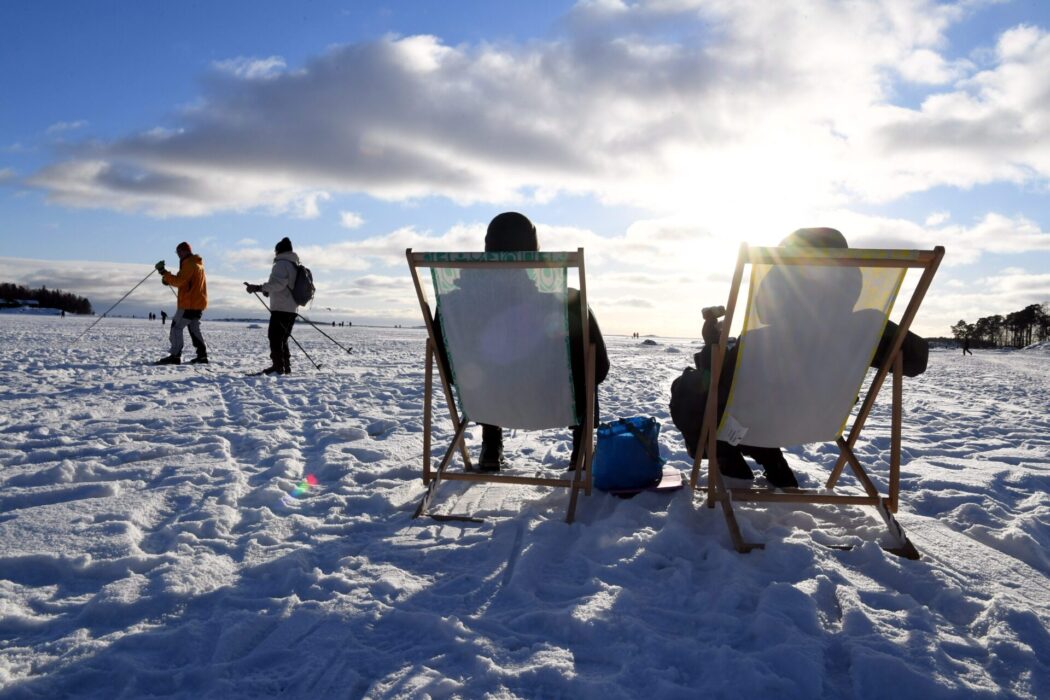 Folk skidar, sitter i solstolar i vintersolen