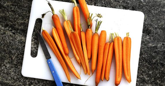 Skärbräda av plast, morötter och kniv.