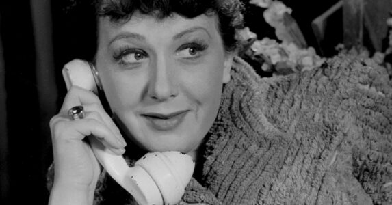 En kvinna med en gammaldags telefonlur vid örat.