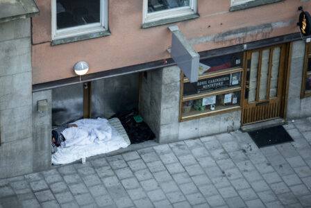 En hemlös person sover i en port.