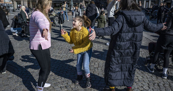 En flicka skojar med någon på ett torg.